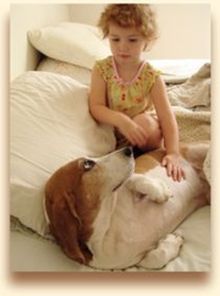 Little girl on bed with basset hound